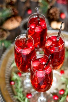 three glasses filled with red liquid on top of a plate