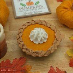 a pumpkin pie sitting on top of a wooden table next to other fall leaves and decorations