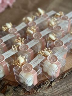 small clear boxes filled with candles on top of a wooden table next to pink flowers