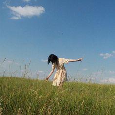 a woman in a field reaching for a frisbee