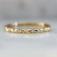 a yellow gold ring with three diamonds on it, sitting on top of a white surface