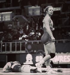 a woman standing on top of a wrestling mat next to another wrestler in a black and white photo