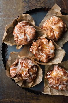 cinnamon rolls with icing sitting on top of a black plate next to a cupcake tin