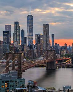 the city skyline is lit up at sunset with skyscrapers and bridges in the foreground