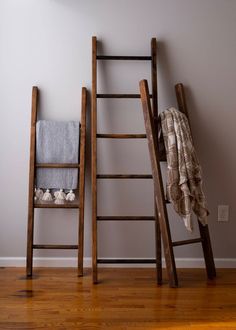 two wooden ladders leaning against the wall next to a towel rack with towels on it