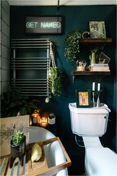 a bathroom with green walls and plants on the shelves above the toilet, along with a sign that says get naked