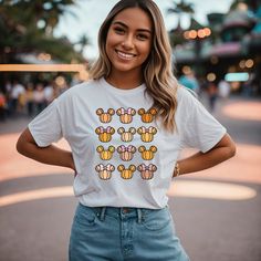 a woman standing in the street wearing a mickey mouse t - shirt and denim shorts