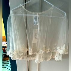 a white blouse hanging on a hanger in front of a door with a tag attached to it