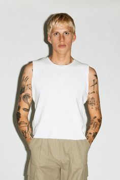 A 90's counter-culture sleeveless muscle tank. Distressed hems, cropped waistband and raw-edge seams add a gritty edge to a minimalist bicep-revealing silhouette. Constructed in an ultra-thick 2-ply ribbed cotton to be worn solo as a statement on its own. Fitted Cropped Muscle Tee For Summer, Cropped Muscle Tee For Everyday Summer Wear, Summer Fitted Cropped Muscle Tee, Cropped Muscle Tee For Summer, Summer Muscle Tee With Dropped Armholes, Cropped Muscle Tee With Relaxed Fit For Summer, White Cropped Tank Top For Streetwear, Summer Cropped Muscle Tee Relaxed Fit, Summer Relaxed Fit Cropped Muscle Tee