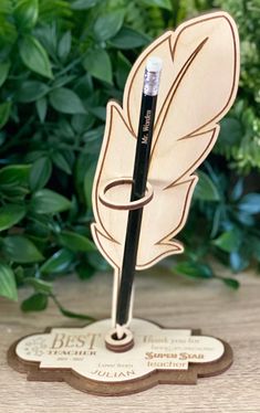 a wooden pen holder with a feather on it and the words best written in black ink