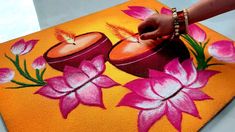 a person is painting flowers on an orange surface with pink and yellow colors in the background