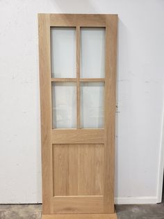 a wooden door with frosted glass on the top and bottom panel, in front of a white wall