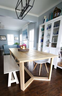 a dining room table with two benches in front of it and shelves on either side