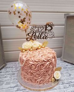 a pink and gold birthday cake with balloons