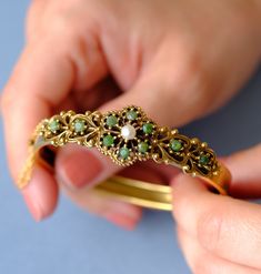 This is a beautiful gold-plated (vergoldet) bangle, created around the 1940s. The bangle features intricate detailing with a central floral motif. It is adorned with 10 jade stones and a central pearl. The design is reminiscent of the Victorian era. The bottom half of the bangle is plain, free of design. The bangle can be easily opened and closed with a box clasp, and an additional safety chain ensures it is secure and easy to put on and take off. Condition: Excellent vintage condition, with all Vintage Yellow Gold Bangle Cuff Bracelet, Vintage Yellow Gold Bangle, Vintage Yellow Gold Cuff Bracelet With Intricate Design, Victorian Gold Bangle Cuff Bracelet, Antique Yellow Gold Cuff Bangle Bracelet, Vintage Yellow Gold Hallmarked Cuff Bracelet, Antique Gold Bangle With Jubilee Bracelet, Vintage Yellow Gold Bangle With Jubilee Bracelet, Elegant Antique Gold Bangle