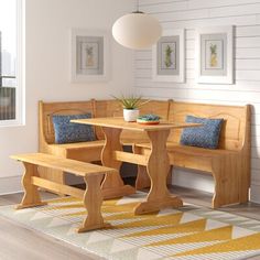 a wooden table and benches in a room with white walls, rugs and pictures on the wall