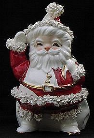 a santa clause figurine sitting on top of a black surface with his hands in the air