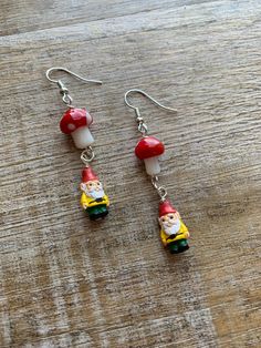 "Handmade cottagecore  gnome mushroom earrings 🍄 Regular Earrings- 2.25 inches long. (READY TO SHIP!) Tunnel Earrings- 2.75 inches long.  Clip On Earrings- 2.25 inches long. measurements are approximate.  Glass mushroom and ceramic gnome beads. Lightweight. These earrings are inspired by the \"cottagecore\" aesthetic, which romanticizes a simple and idyllic rural lifestyle. They can make a lovely addition to an outfit with a similar aesthetic or add a touch of whimsy to any ensemble." Charms For Earrings, Cottagecore Gnome, Tunnel Earrings, Elf Earrings, Ice Cream Shoes, Gnome Earrings, Christmas Purse, Cottagecore Earrings, Elf Gnome