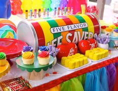 a candy bar with gummy bears and cupcakes on the table in front of it