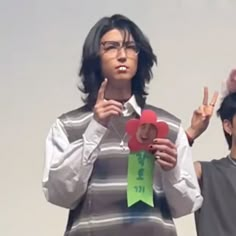 two young men standing next to each other holding up peace signs and fingers in the air