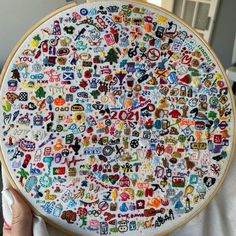 a person holding up a cross stitched circle with many different stickers on it