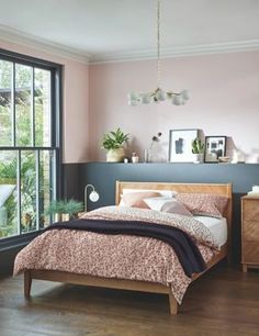 a bed room with a neatly made bed next to a window and potted plants