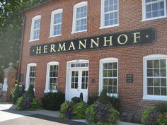 the building has many windows and plants on it's front porch, along with a sign that says hernann hof