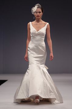 a woman in a white wedding dress walking down the runway