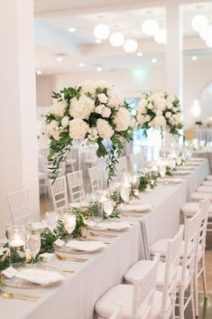 a long table is set with white flowers and candles