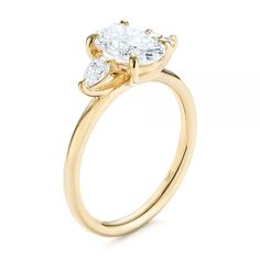 a yellow gold engagement ring with two pear shaped diamonds on the side and an oval center stone