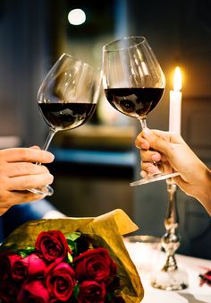 two people toasting with red wine and roses