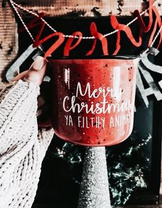 a person holding a mug with merry christmas ya filthy santa written on it