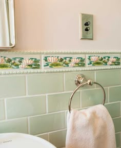 a white towel hanging on the side of a bathroom wall next to a sink and mirror