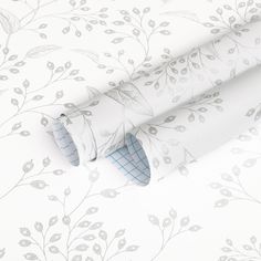 a white wallpaper with leaves and vines on it's side, next to a roll of toilet paper