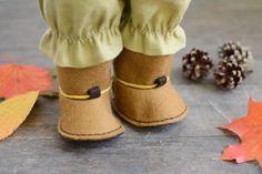 a pair of brown boots sitting on top of a wooden floor next to autumn leaves