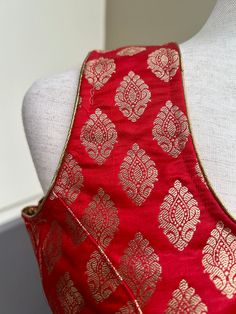 Pure Banarasi Red Color Blouse with Gold Buttis in Zari Weaving. Comes with Cups attached to the blouse. Please note : Blouses has margin to open 2 sizes up. Item : Ready to Wear BlouseColor : Red Sleeves : Sleeveless (Does not come with Sleeves)Blouse Fabric : Pure Banarasi SilkBlouse Fitting : Princess Cut Lining : Yes, it is fully lined Padded or Non-Padded : Padded Closure: Back Closure with hooks.Ready-to-Wear : YesDisclaimer - :-This is a Standard Size blouse. We do not guarantee perfect f Traditional Sleeveless Blouse Piece For Eid, Traditional Sleeveless Blouse For Eid, Red Festive Blouse For Eid, Festive Traditional Drape Tops For Eid, Festive Tops With Traditional Drape For Eid, Resham Embroidery Blouse For Eid Celebration, Sleeveless Chanderi Blouse With Resham Embroidery, Festive Zari Work Tops For Celebration, Eid Celebration Blouse With Resham Embroidery