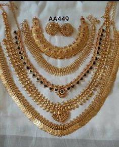 gold necklaces and bracelets are displayed on a white sheet with the words aa459