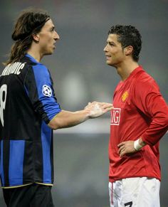 two men standing next to each other on a soccer field with one holding his hand out