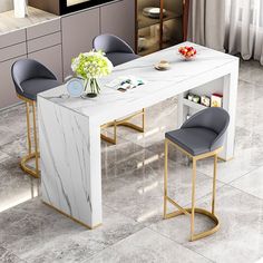 a white marble dining table with two grey chairs next to it and a vase filled with flowers