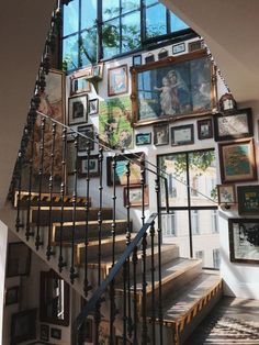 a staircase with many pictures on the wall and framed artwork above it, along with an iron handrail