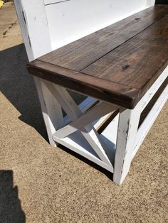 a wooden bench sitting next to a white wall