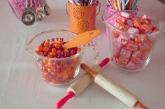 there are many candy items in the cups on the table with utensils next to them