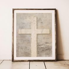 a white cross is on the wall next to a wooden floor and a framed photograph