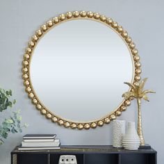 a large round mirror sitting on top of a wooden table next to a vase and plant