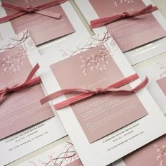 the wedding stationery is laid out on top of each other, with pink ribbon