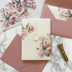 some pink and white cards with flowers on them next to a gold wax stamper