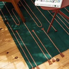 a table with a book on top of it next to a green rug and chair