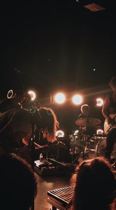 a group of people that are standing in front of a stage with some lights on