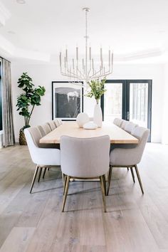 a dining room table with chairs and a vase on top of it in front of a chandelier