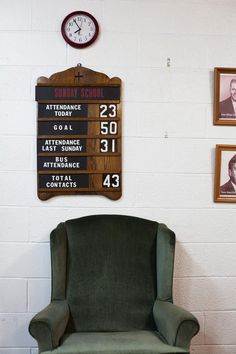 a green chair sitting in front of a wall with pictures on it and a clock mounted to the wall